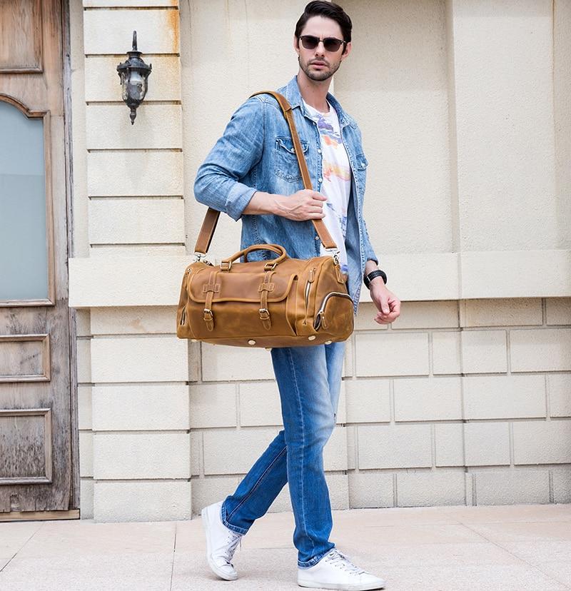 Man in Blue Jeans walking on sidewalk carrying a leather duffle bag