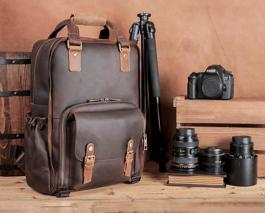 Leather Camera bag shown on wood background with lenses by its side sitting upright 