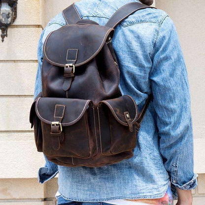 Man standing in blue jean jacket carrying our Acadia Dark Brown Leather Backpack over his shoulders