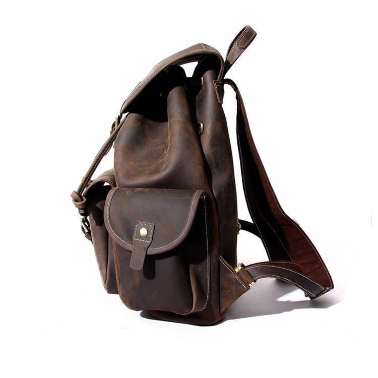 Acadia Large Leather Backpack side view standing upright and showing large leather shoulder straps on a white background