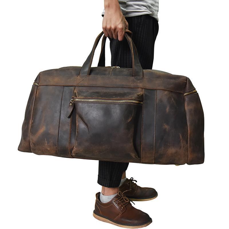 man with black pants and brown shoes carrying the Carter large Duffel weekender leather bag on white background