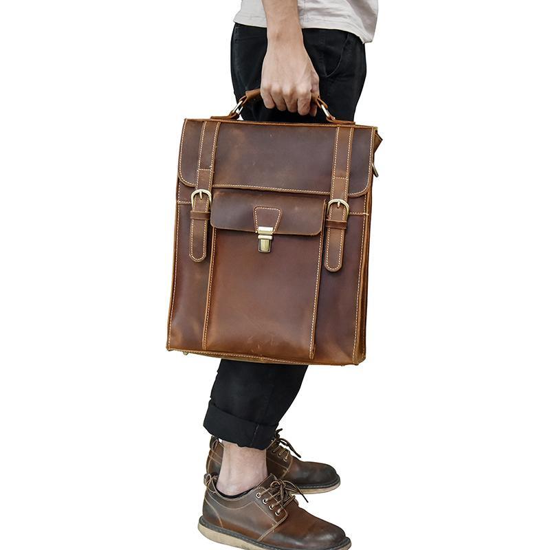 man white white t-shirt and black pants and brown shoes carrying a leather Badlands backpack by teh leather handle