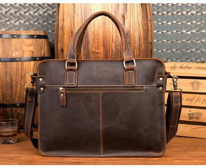 Front view of Bryce leather briefcase showing leather tip zippered shut and brown leather handle with shoulder strap on wooden table