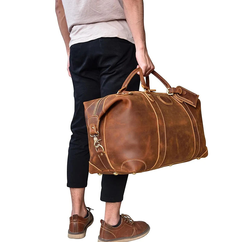 man with black pants and white shirt holding a Dayton Duffle Weekender leather bag by handle on a white background