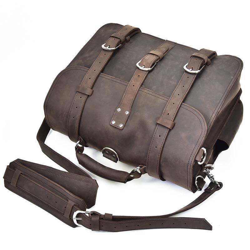 Cumberland Messenger bag paying on its side showing three buckle flaps and dark brown shoulder strap