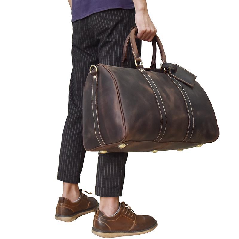 man with black pants a purple shirt holding a Yukon weekender duffle bag full view